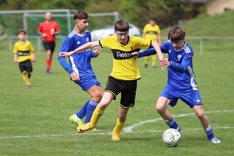 Un groupe de jeunes garçons jouent au football sur un terrain.