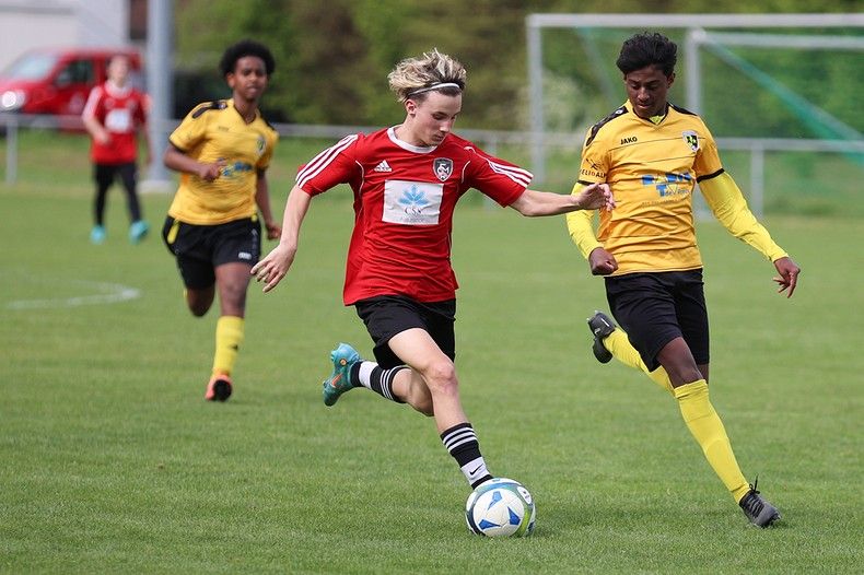 Un groupe de jeunes hommes jouent au football sur un terrain.