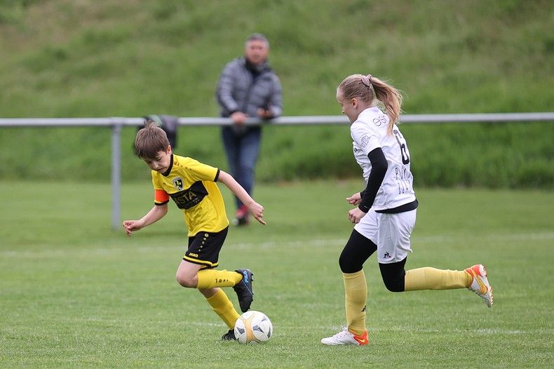 Un garçon et une fille jouent au football sur un terrain.