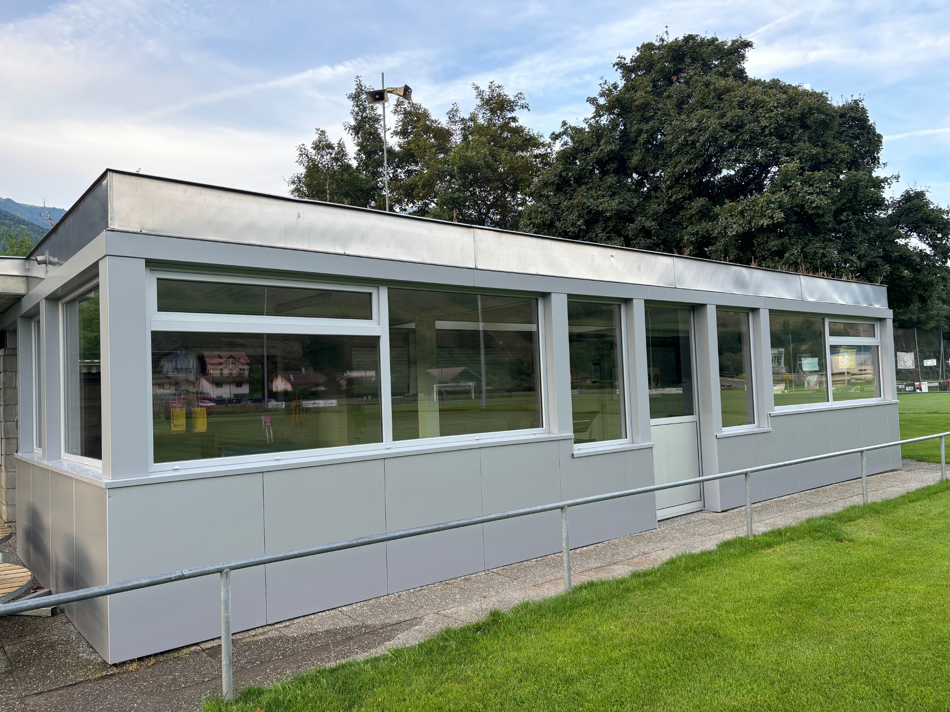 Un bâtiment avec beaucoup de fenêtres est situé au sommet d'un champ vert luxuriant.