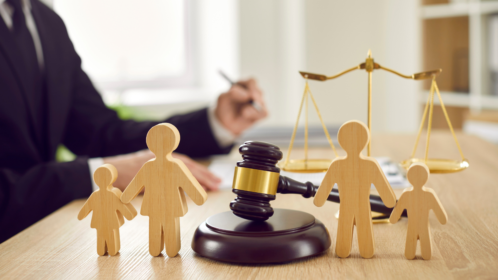 Courtroom-themed desk scene with gavel, scales of justice, and paper figures representing a family dispute