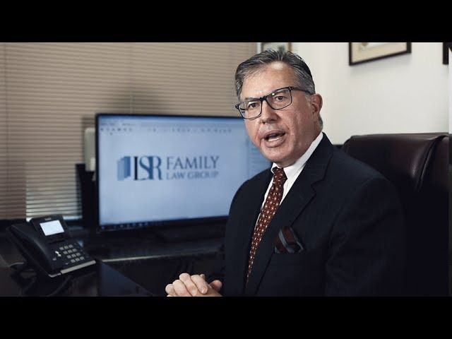 Attorney speaking in a law office beside a desk phone and monitor displaying a law firm logo