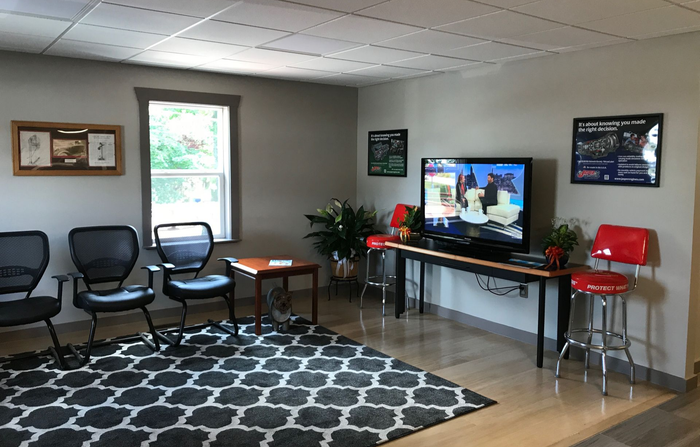 Waiting room with chairs, TV, plants, and a geometric rug | Gateway Automotive Inc.