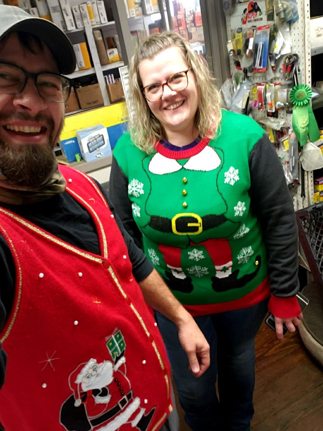 Two people in holiday sweaters smiling indoors | Gateway Automotive Inc.