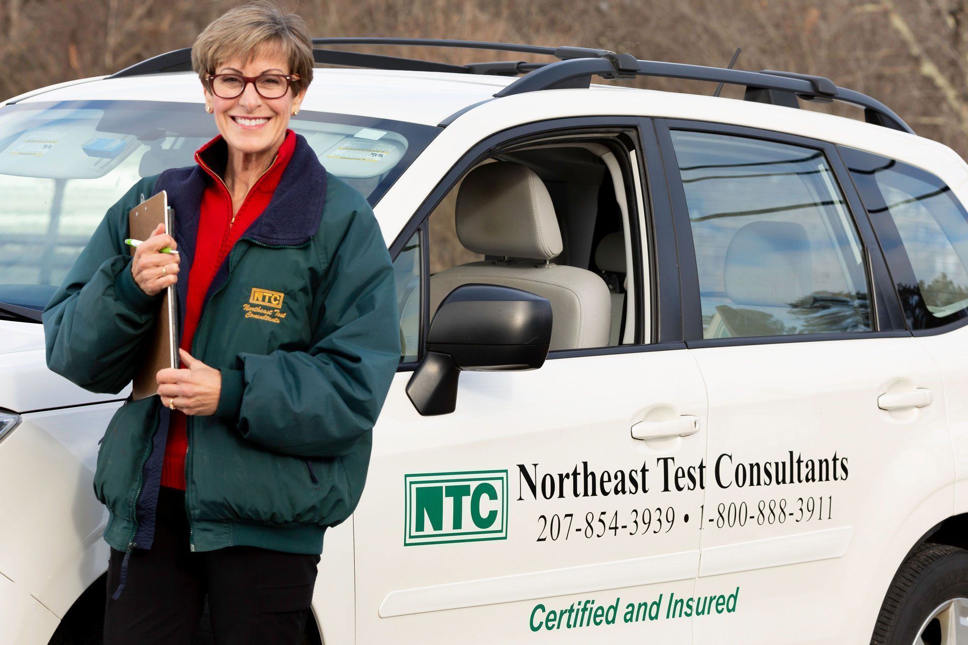 Person standing by a white company SUV holding a pole, with 