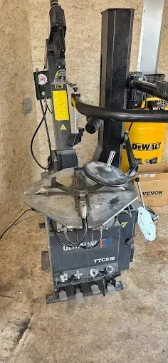 Machine à changer les pneus en panne dans un atelier, avec un outil DeWalt noir et jaune et des boîtes à proximité