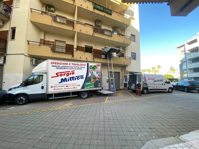 Camion delle consegne parcheggiati accanto a un condominio in una strada soleggiata