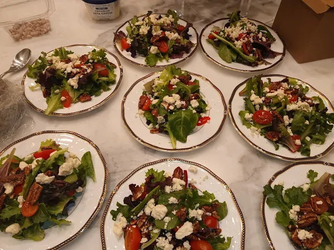 Salads arranged on plates with greens, tomatoes, cheese, and nuts.