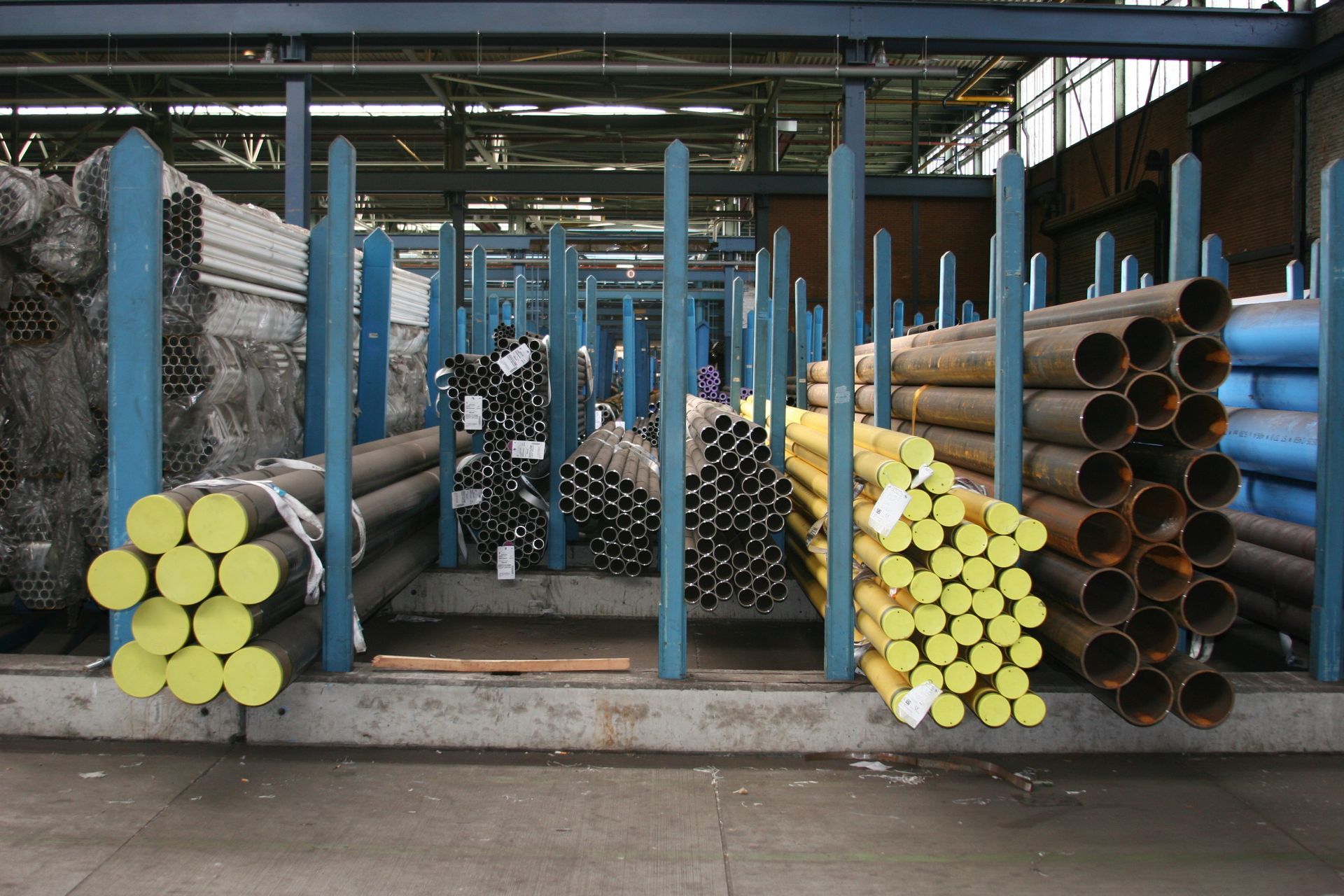 Bundles of steel pipes and tubing stacked in metal storage racks inside a warehouse
