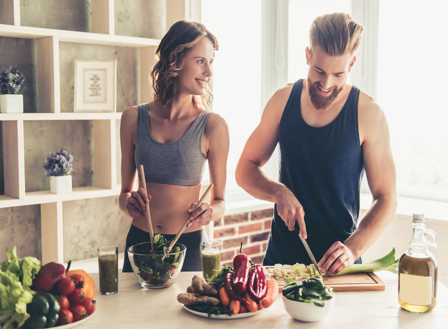 beautiful-young-sports-people-are-talking-and-smiling-while-cooking-healthy-food-in-kitchen-at-home
