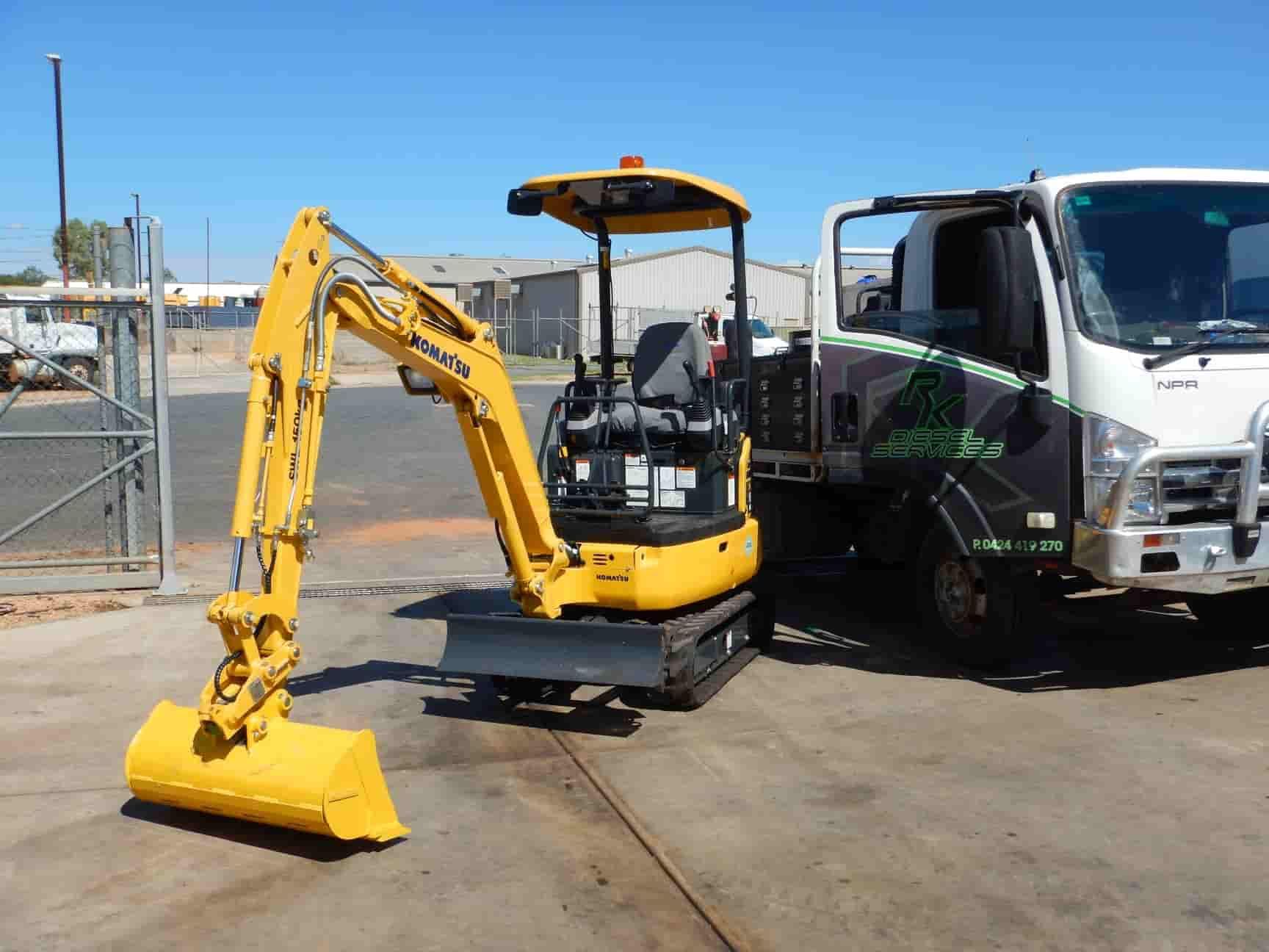 A Yellow Tractor is Parked in a Parking Lot Next to a Truck — RK Diesel Services in Ciccone, NT
