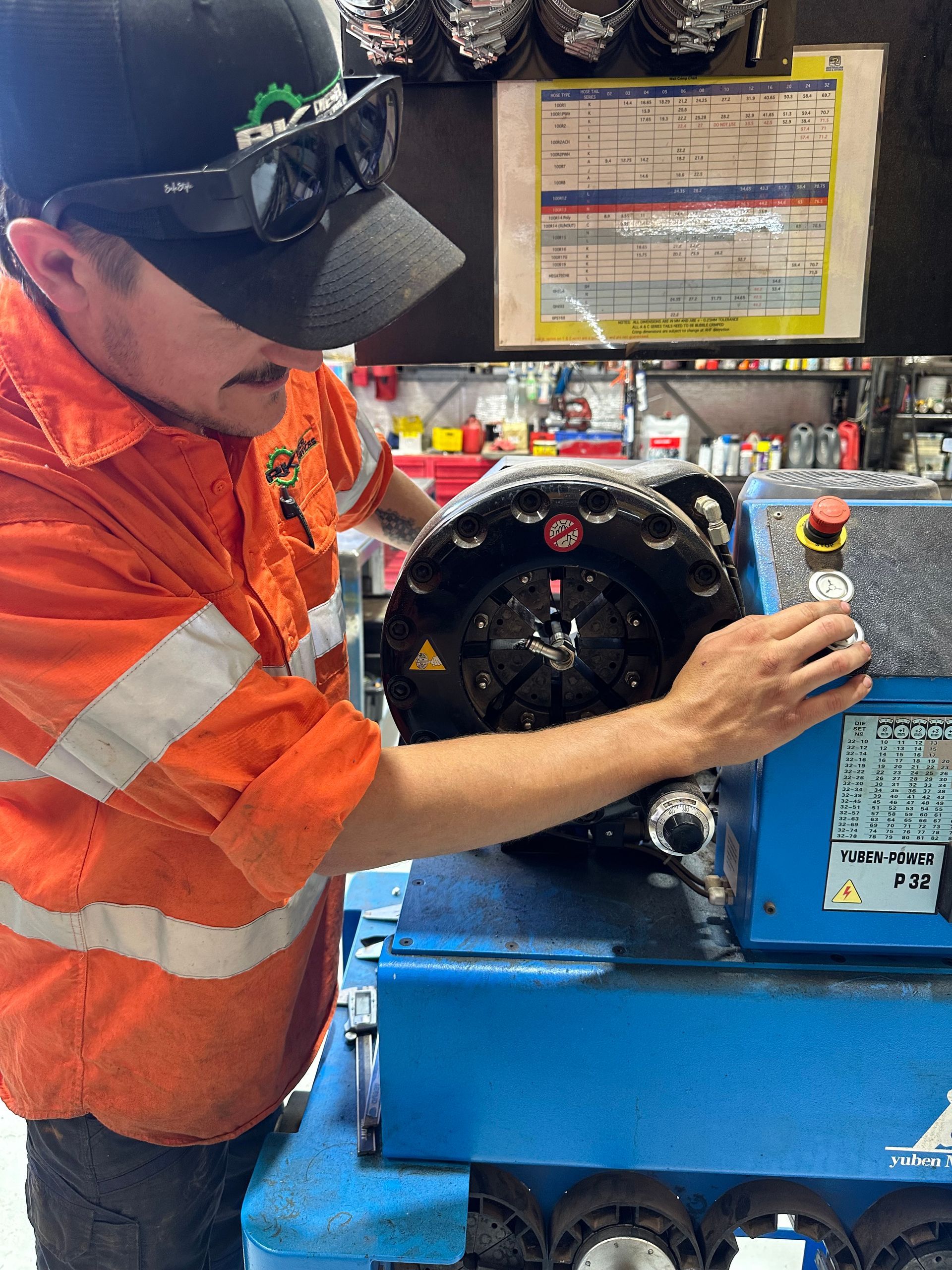 Man in orange shirt operating blue machine, possibly in a workshop. — RK Diesel Services in Ciccone, NT