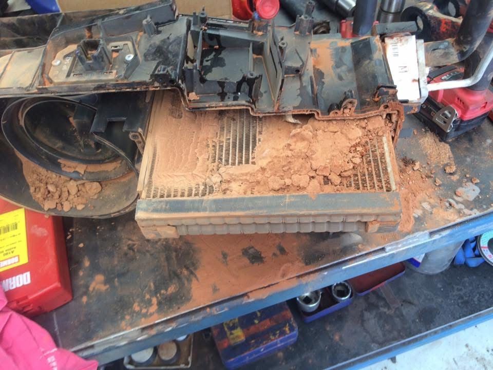 A car's air conditioning system filter covered in thick, reddish-brown dirt, indicating a need for replacement. — RK Diesel Services in Ciccone, NT