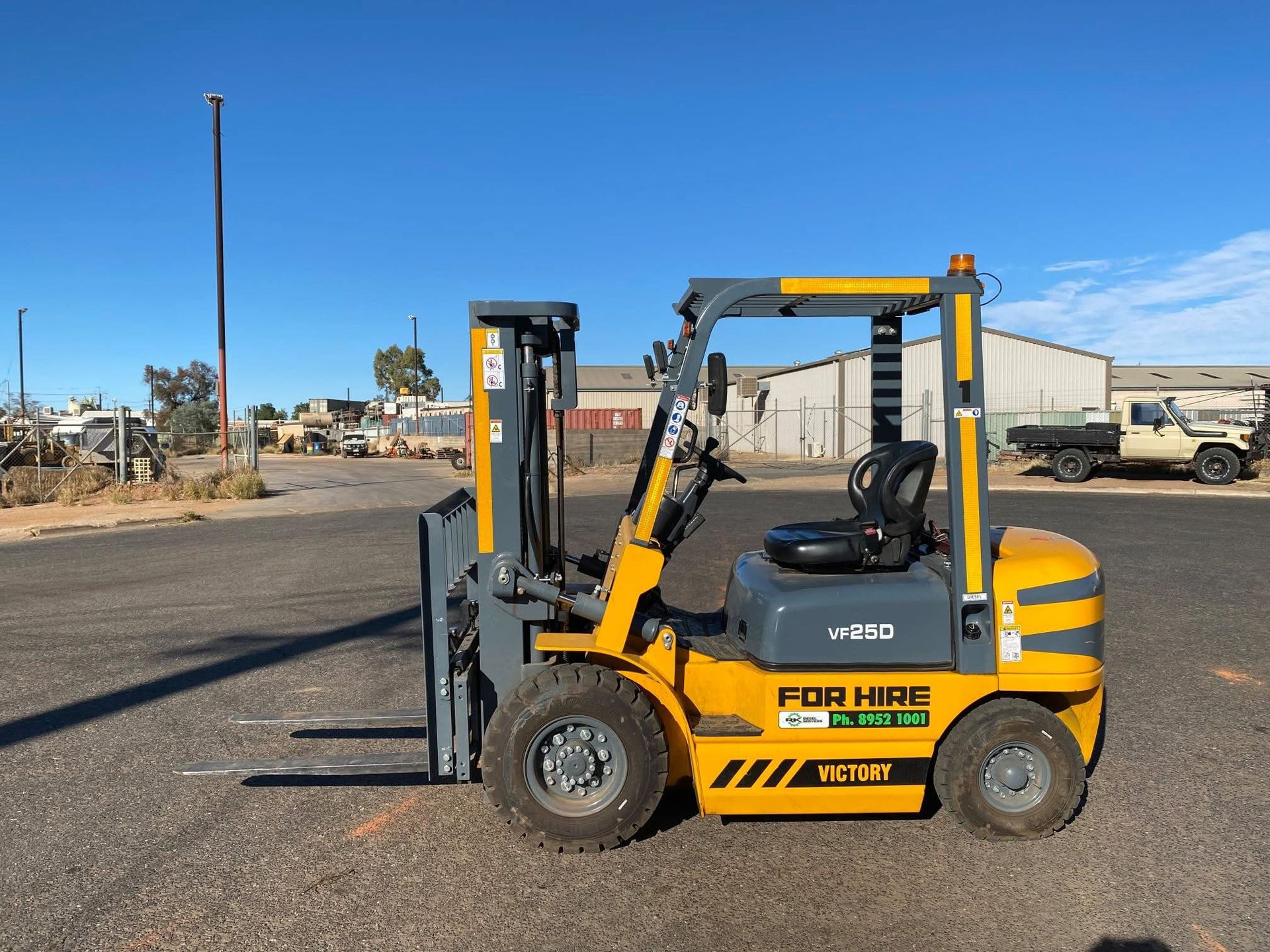 Yellow and grey forklift on an asphalt lot; 