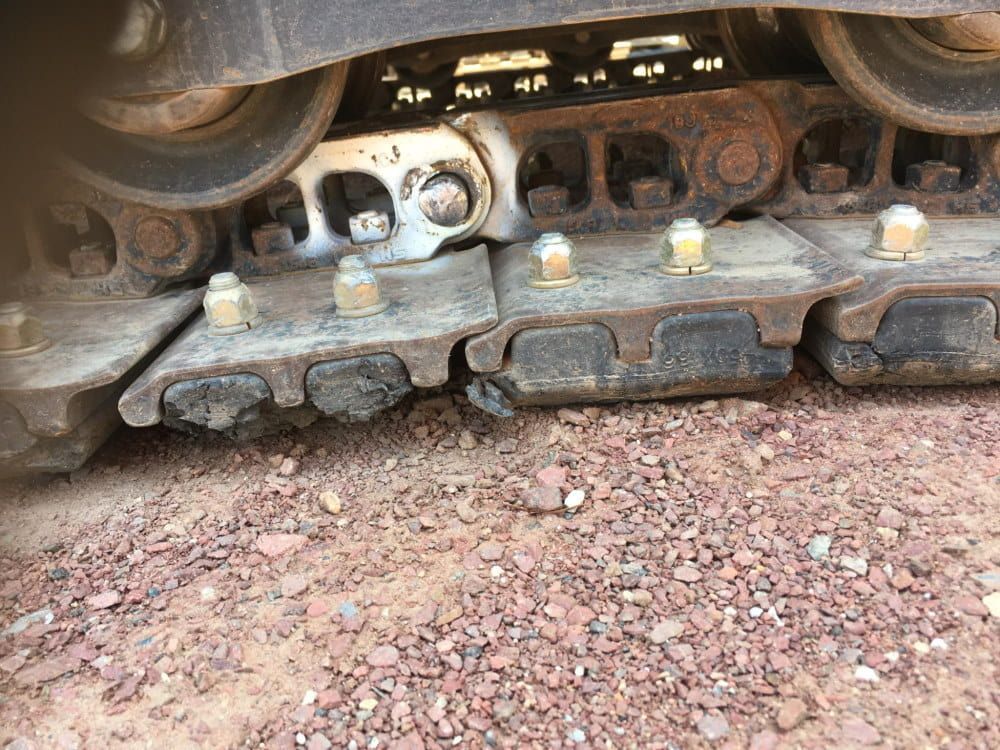A Close Up of a Tractor 's Tracks on a Gravel Road — RK Diesel Services in Ciccone, NT