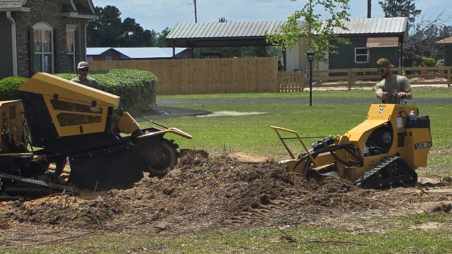 Yellow construction machines digging dirt in a grassy yard near houses