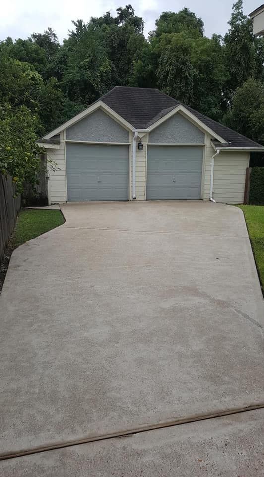 A driveway leading to a house with two garage doors.