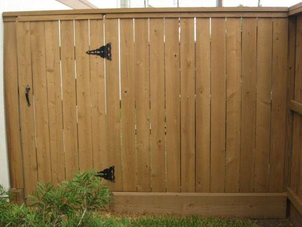 A wooden fence with a black hinge on it
