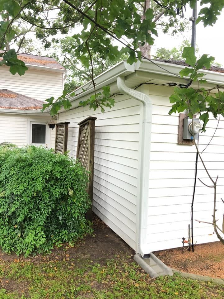 A white house with a gutter on the side of it.
