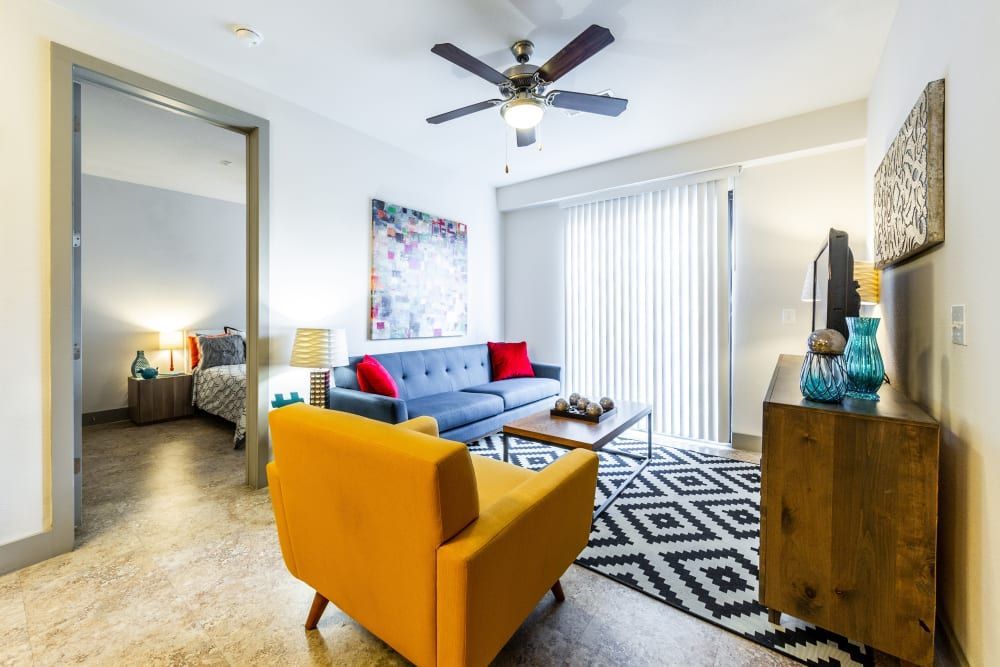 Apartment living room with a couch, chair, coffee table, and ceiling fan at Regents West at 24th in Austin, TX, near West Campus.