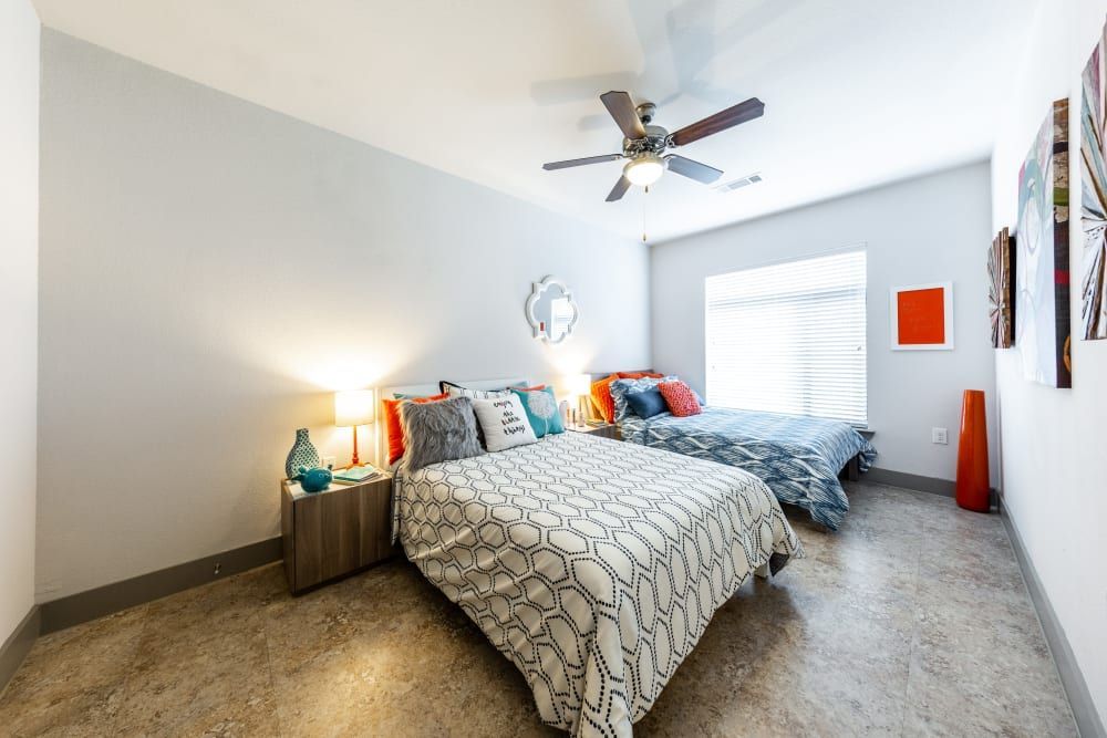 Student apartment bedroom with two beds and a ceiling fan at Regents West at 24th in Austin, TX, near West Campus.