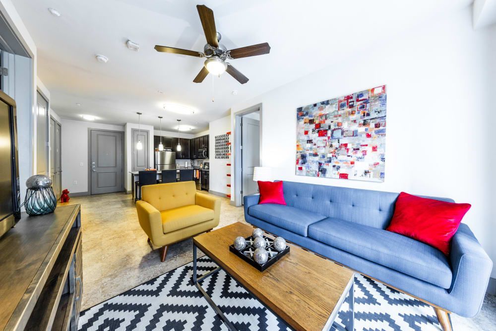 Apartment living room with a couch, chair, coffee table, and ceiling fan at Regents West at 24th in Austin, TX, near West Campus.