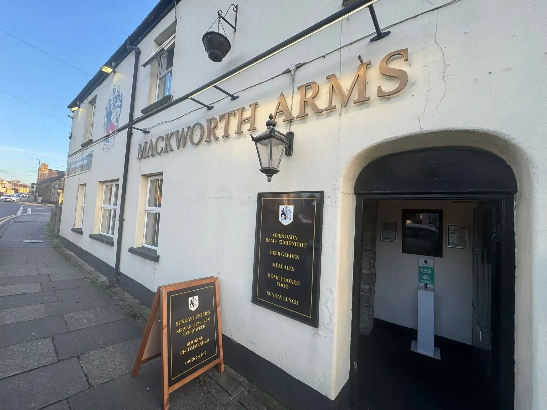 The Mackworth Arms pub with arched doorway, sign, and chalkboard sign on a side.