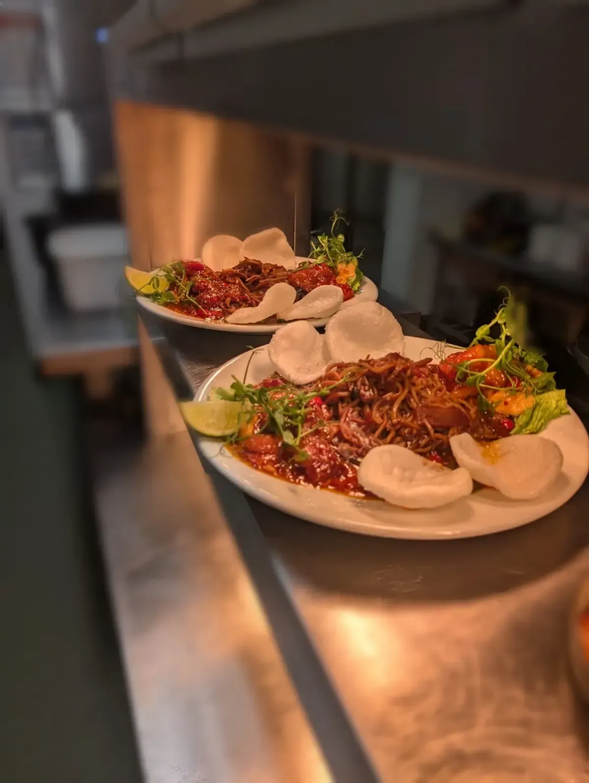 The Mackworth Arms, Laleston, Bridgend | Two plates of food on a stainless steel surface, featuring meat, sauce, garnish