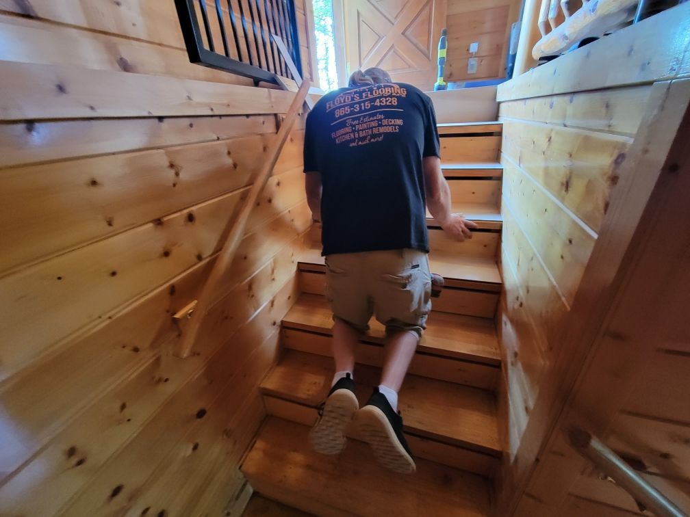 Person climbing wooden stairs in a narrow wood-paneled hallway.