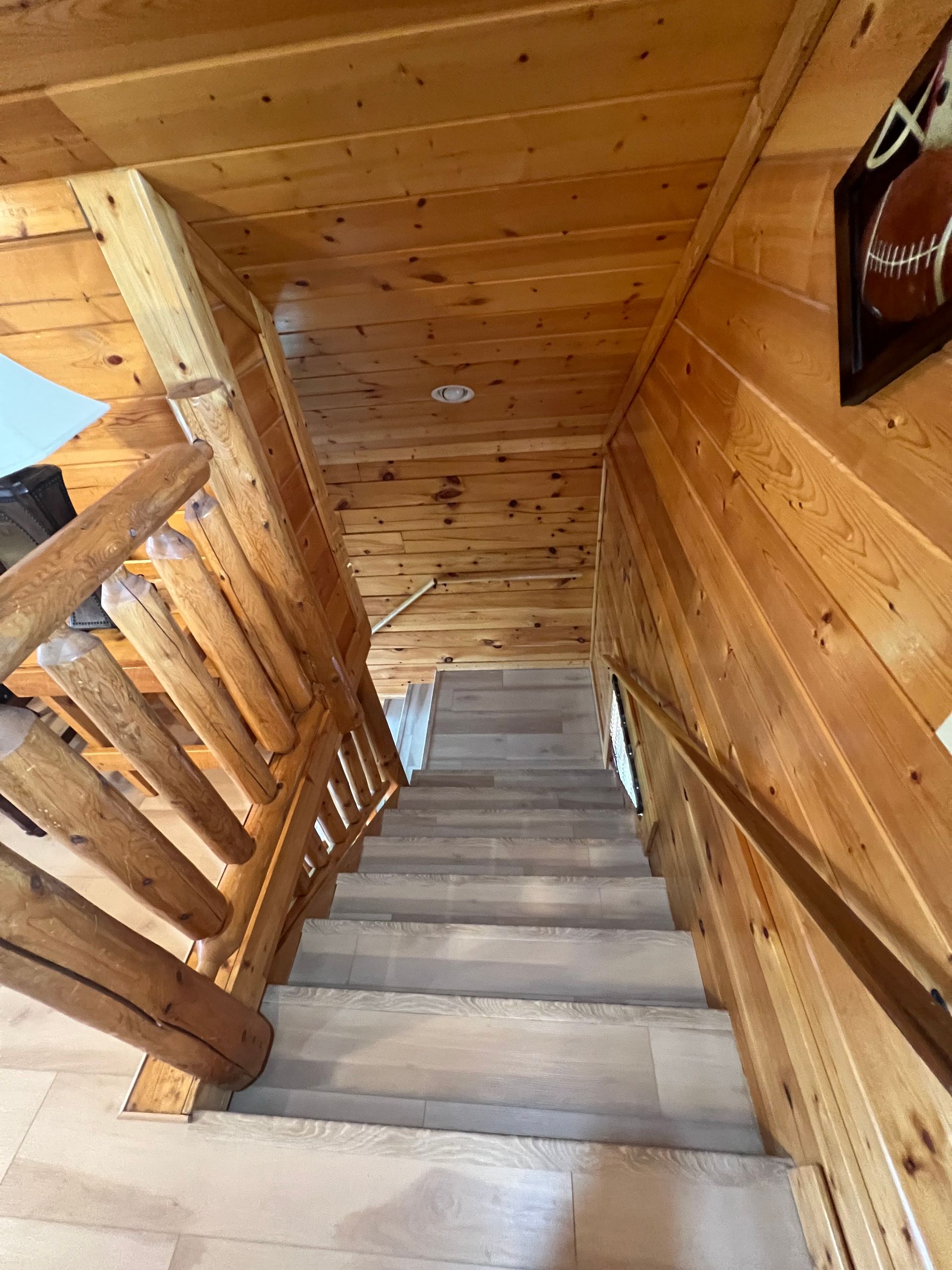 Wooden indoor staircase with a railing, viewed from the top landing.