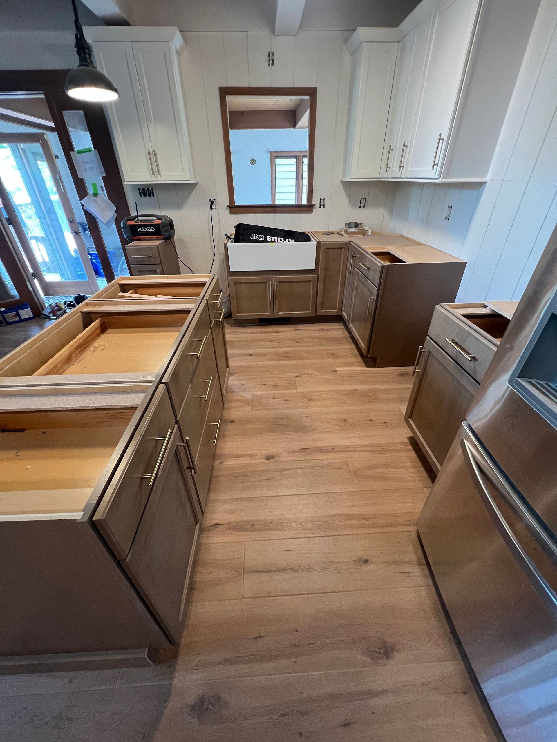 Empty modern kitchen with white cabinets, wood floors, and a stainless-steel stove.