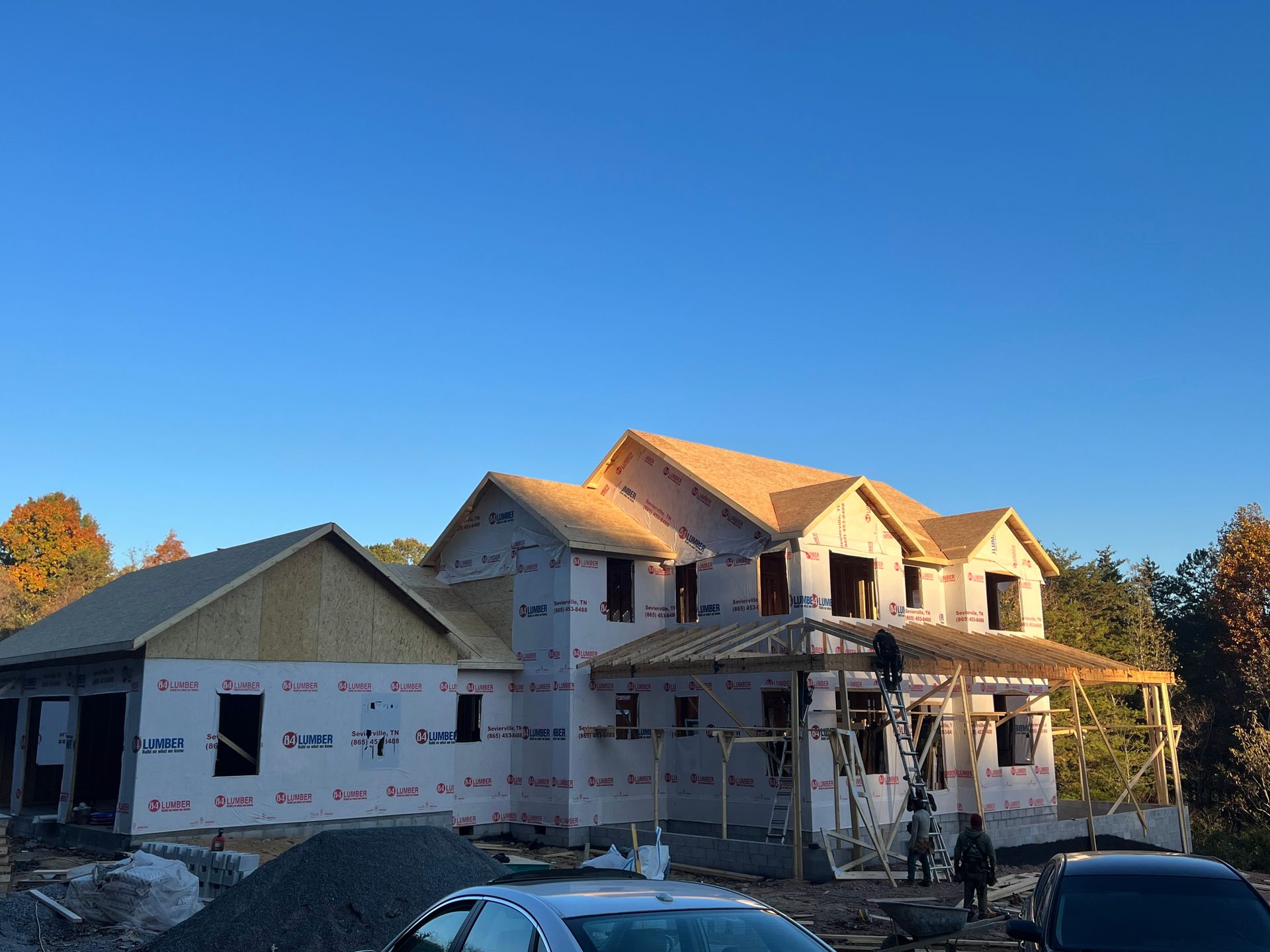 New house under construction with scaffolding, wrapped siding, and blue sky overhead