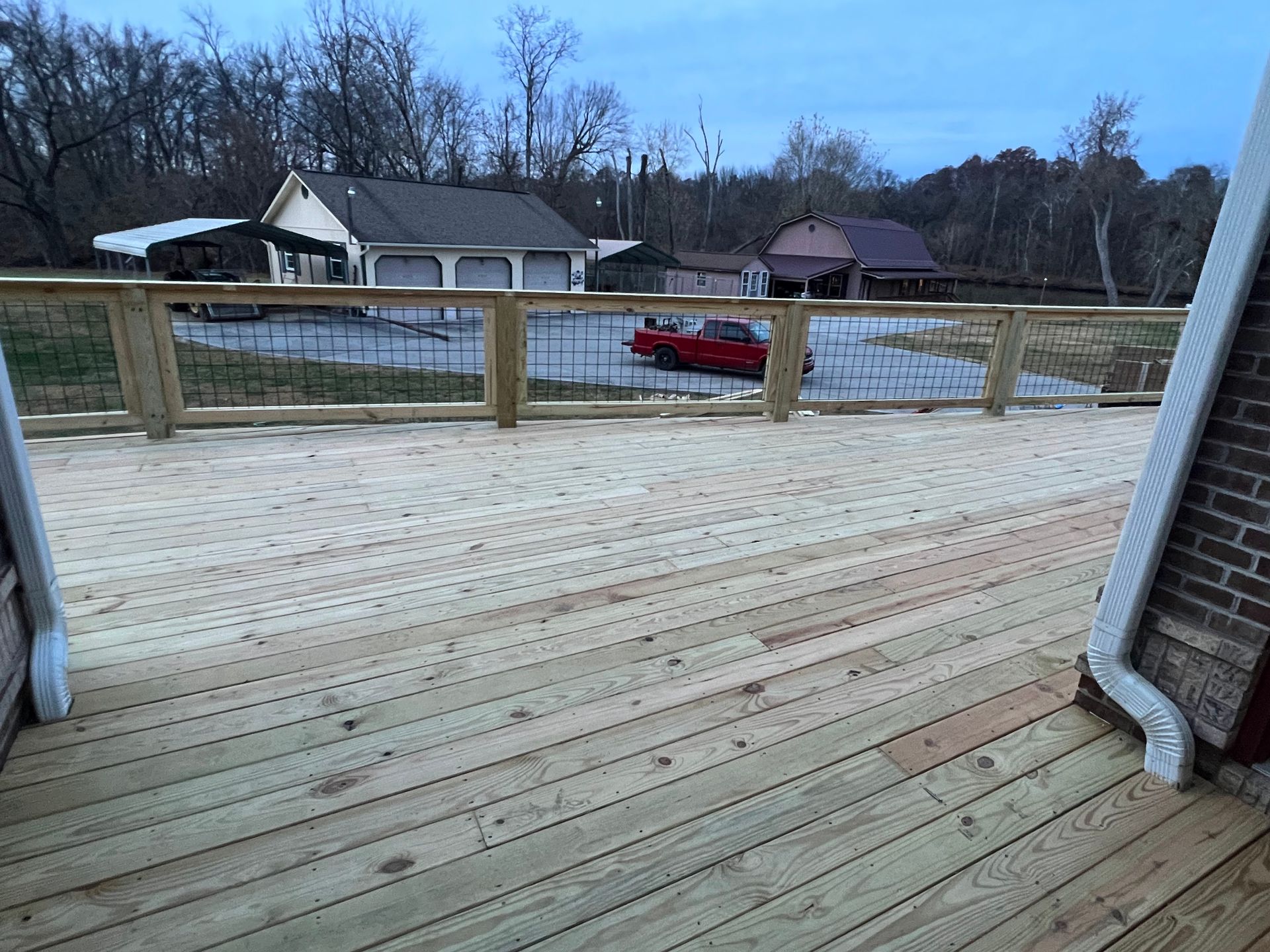 Wooden deck with railing overlooking a suburban street and houses at dusk