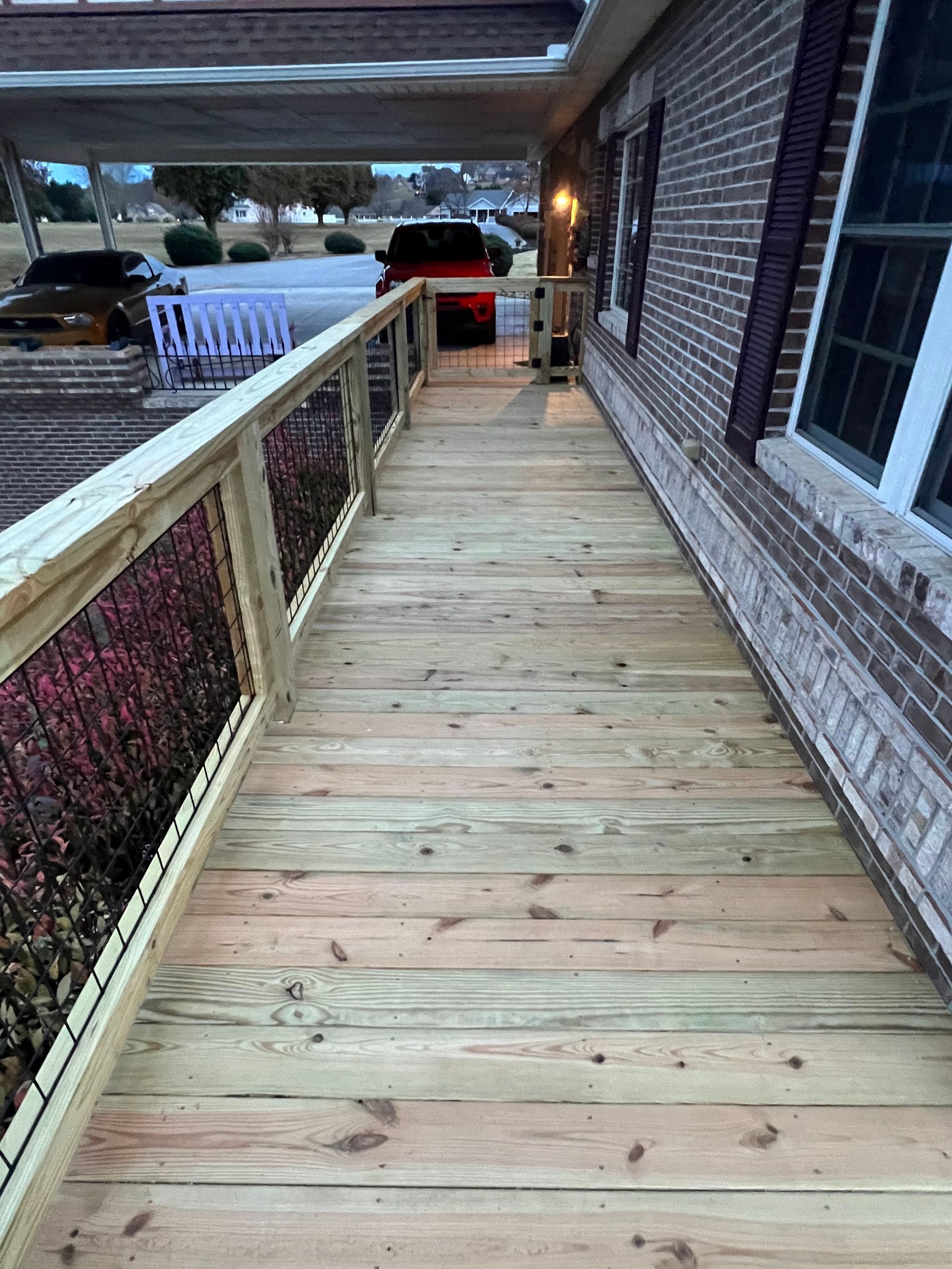 Wooden wheelchair ramp leading to a building entrance, with parked cars nearby.