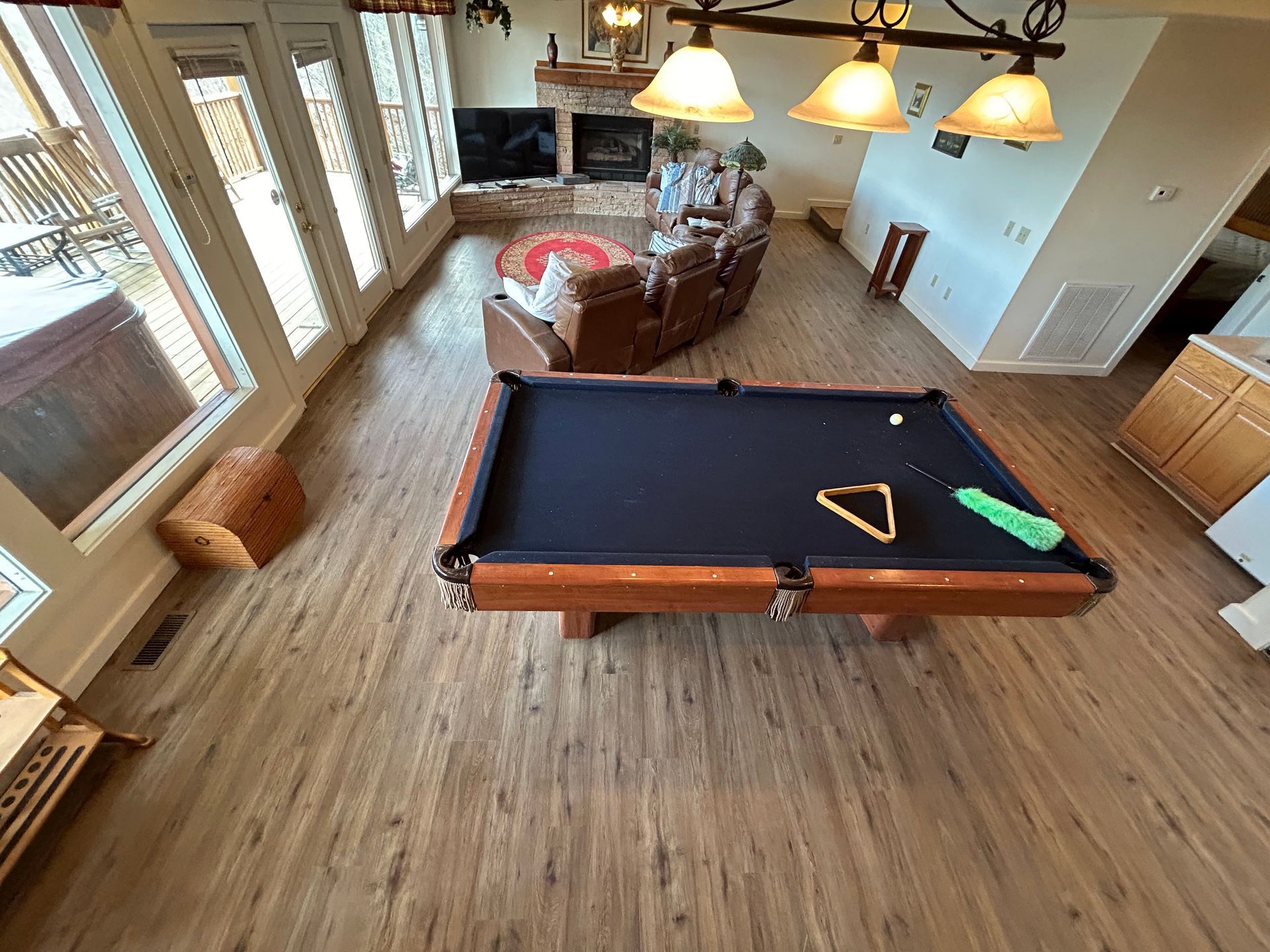 Game room with a pool table, leather chairs, and large windows over wood flooring