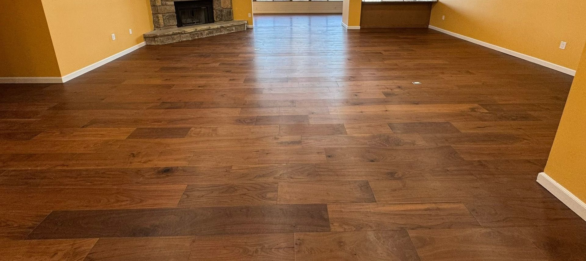 Empty room with dark hardwood floors and tan walls, viewed from the entrance