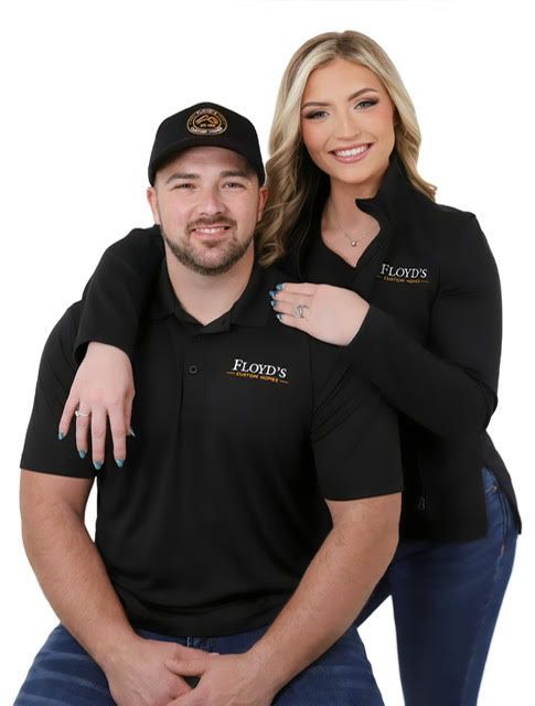 Two coworkers in black polos pose smiling against a white background.