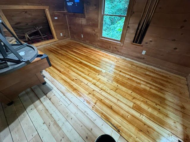 Wooden attic room with freshly finished pine floor, windows, and exposed beams