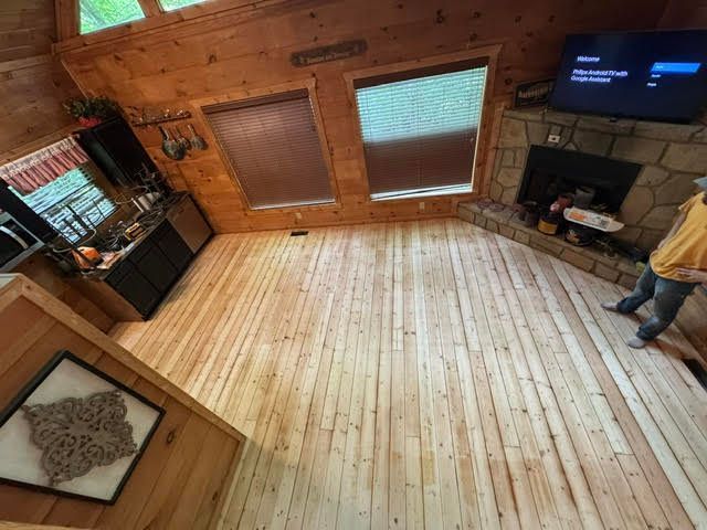 Wood-paneled living room with hardwood floor, fireplace, TV, and a person standing by the wall