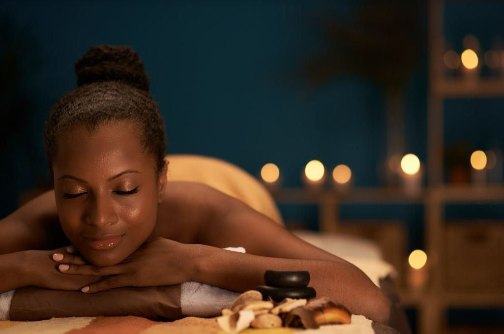 Uma mulher está deitada em uma mesa de massagem com os olhos fechados.