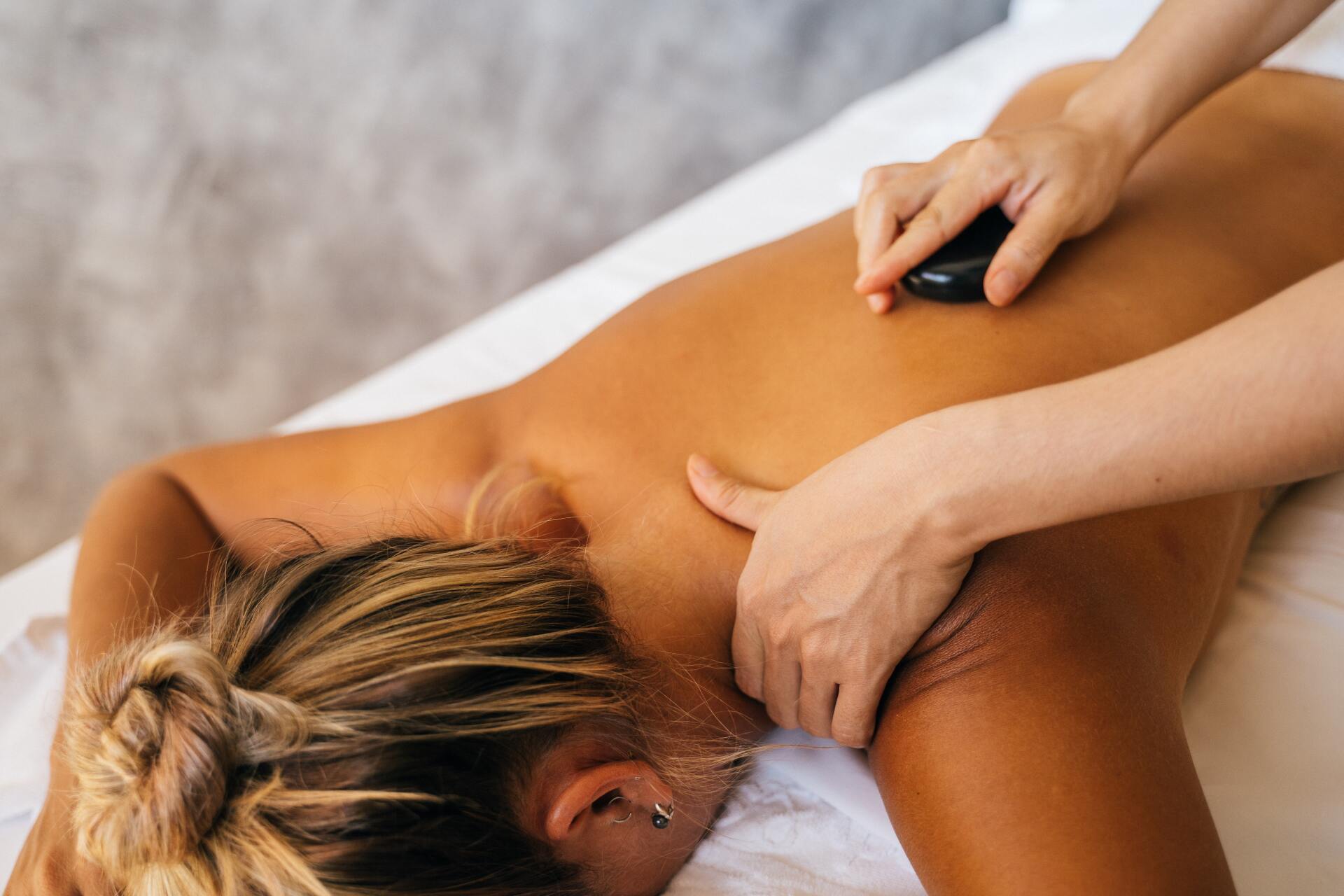 Uma mulher está recebendo uma massagem com uma pedra nas costas.