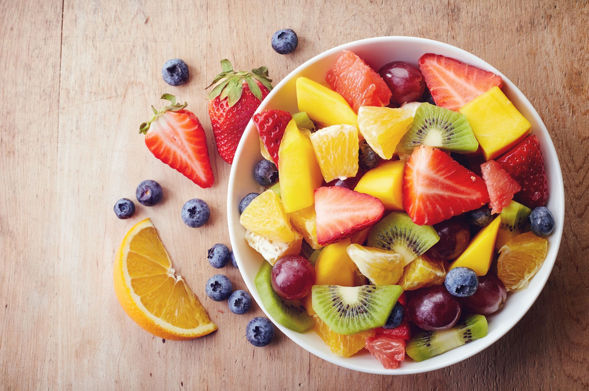 Uma tigela de salada de frutas sobre uma mesa de madeira.