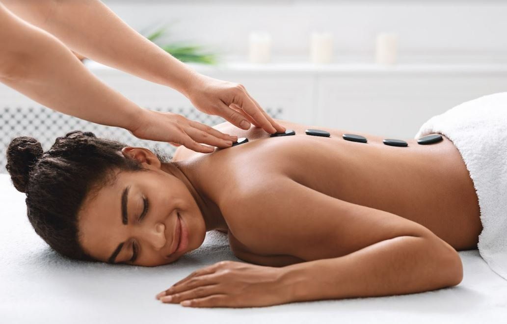 Uma mulher está recebendo uma massagem com pedras quentes em um spa.
