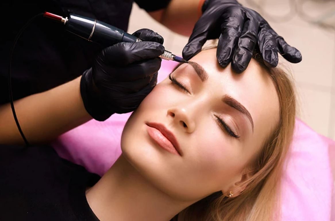 Uma mulher está fazendo maquiagem definitiva nas sobrancelhas.
