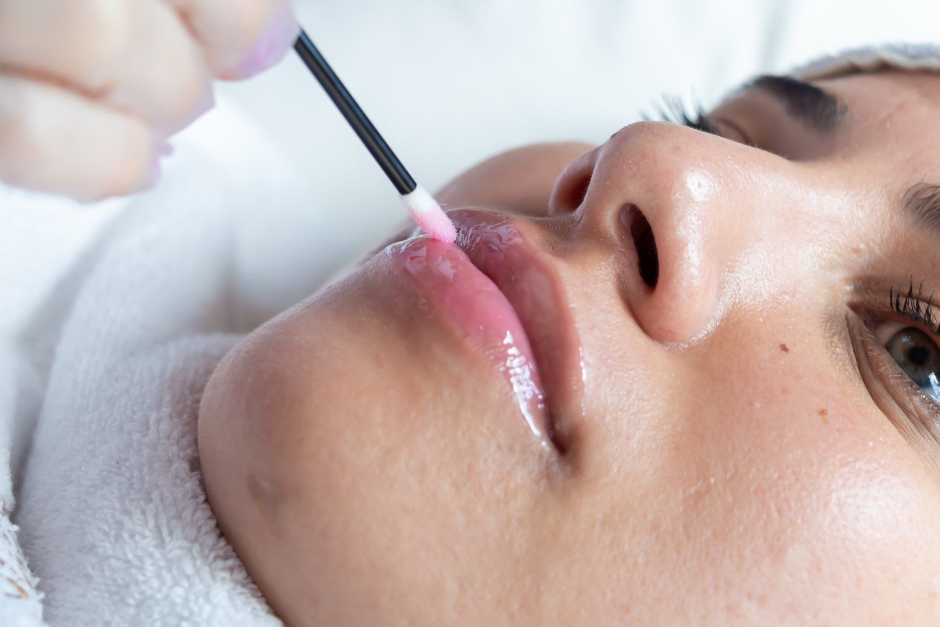 Uma mulher está aplicando brilho labial nos lábios.