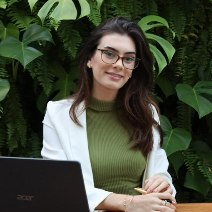 Uma mulher de óculos está sentada em frente a um laptop Acer