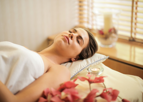 Uma mulher está deitada em uma cama enrolada em uma toalha.