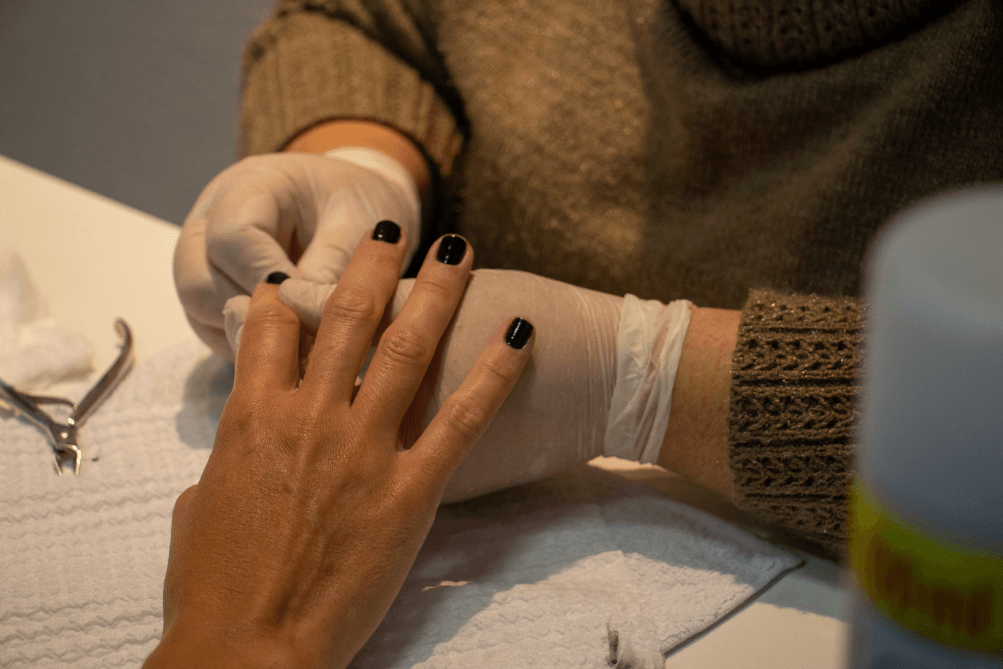 Uma mulher está pintando as unhas por um artista de unhas.