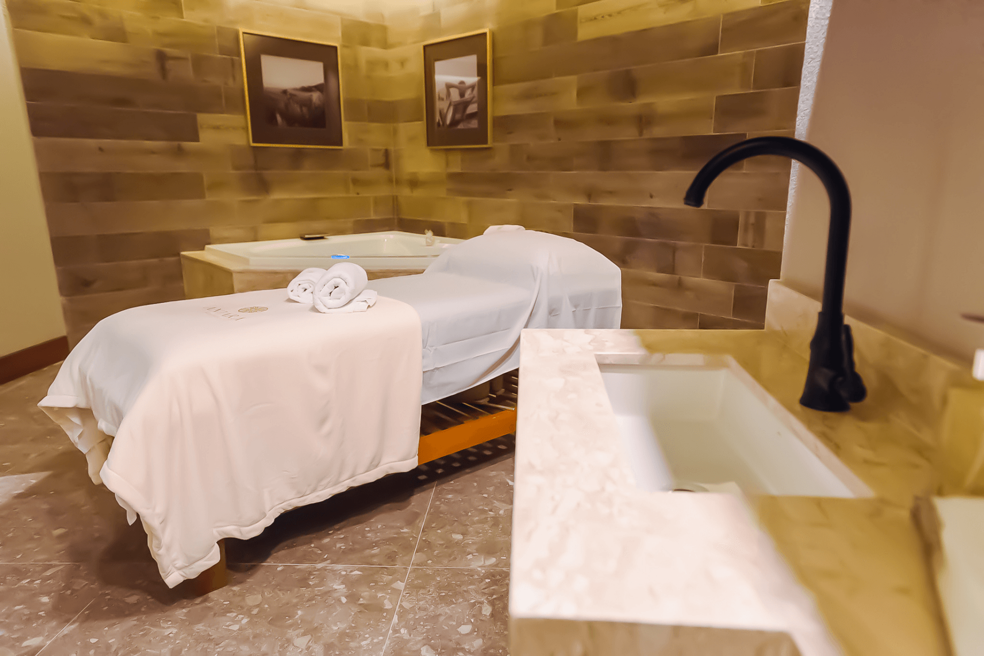 Uma sala de spa com cama de massagem e pia.