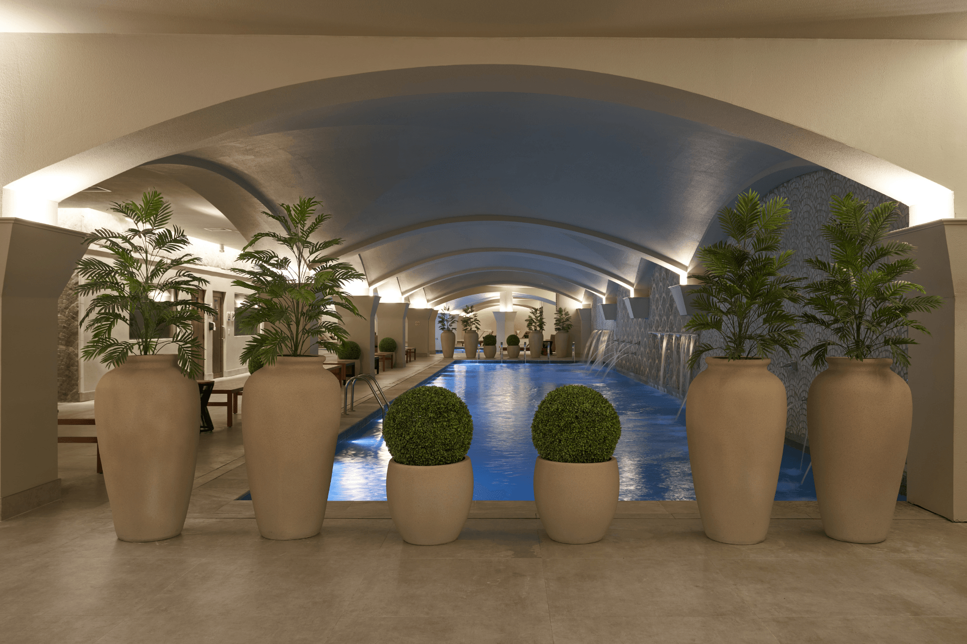 Uma grande piscina interior rodeada por vasos de plantas.